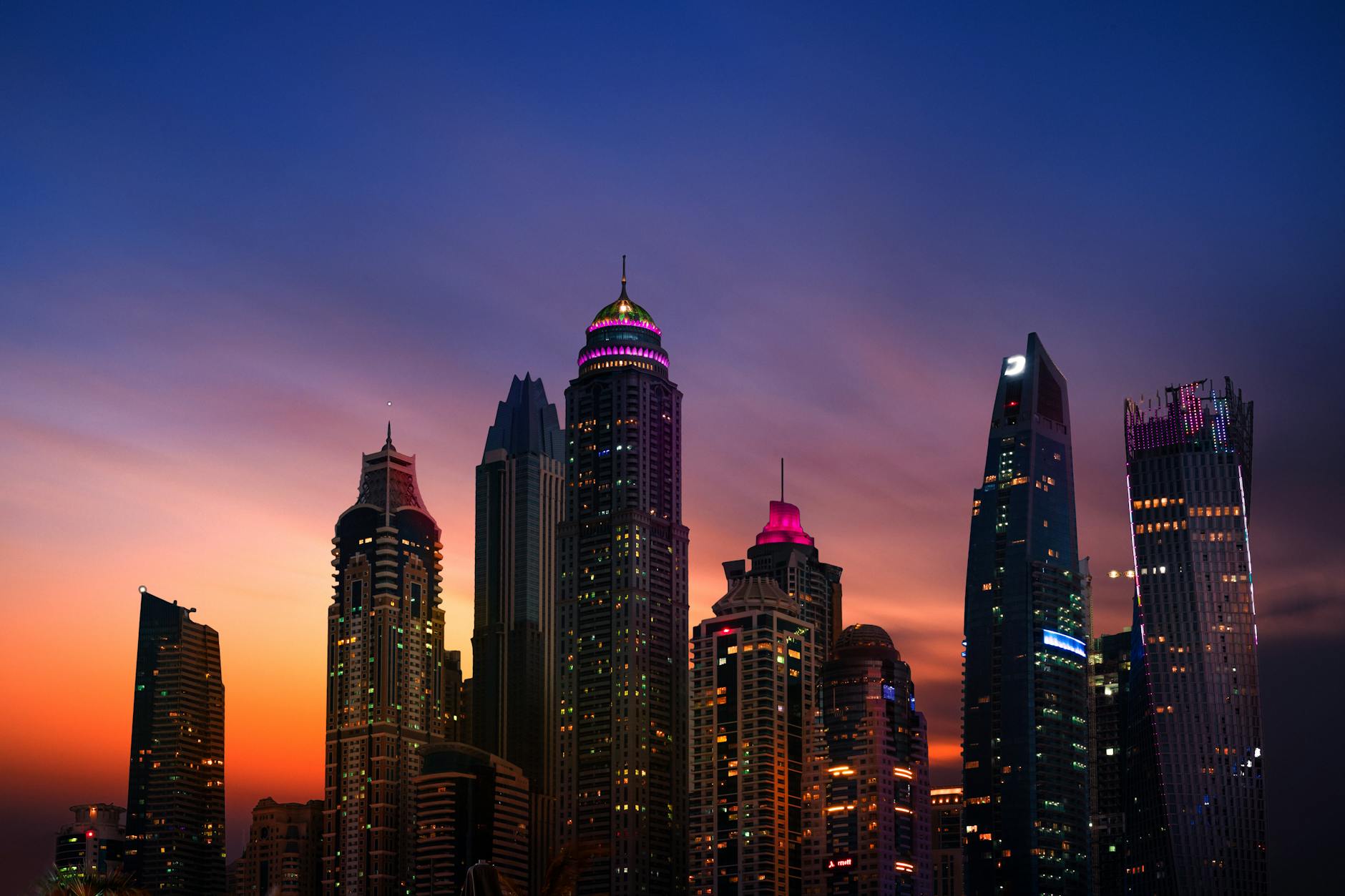 Stunning view of Dubai's skyline with illuminated skyscrapers reflecting a colorful dusk sky.